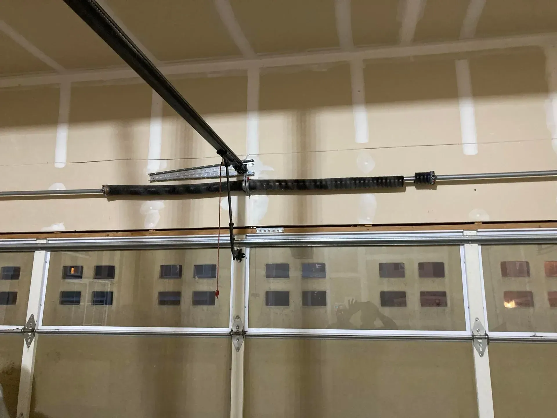 Interior of a garage door with windows and overhead tracks on a beige wall