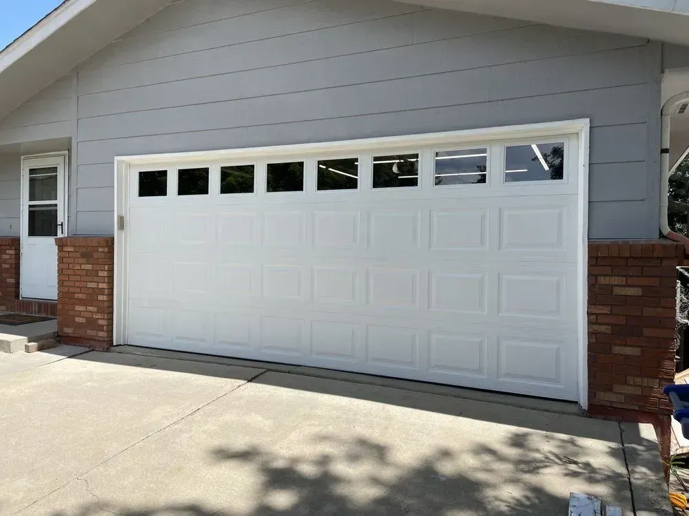 White two-car garage door with small windows in a suburban home exterior