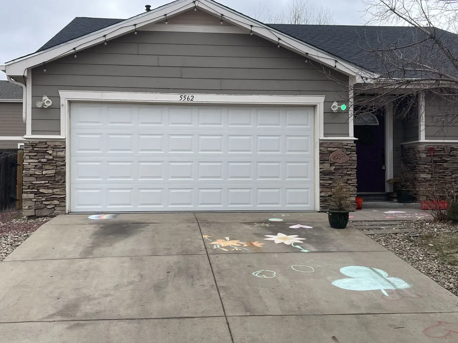 Suburban house with white garage door, concrete driveway, and stone-trimmed entryway