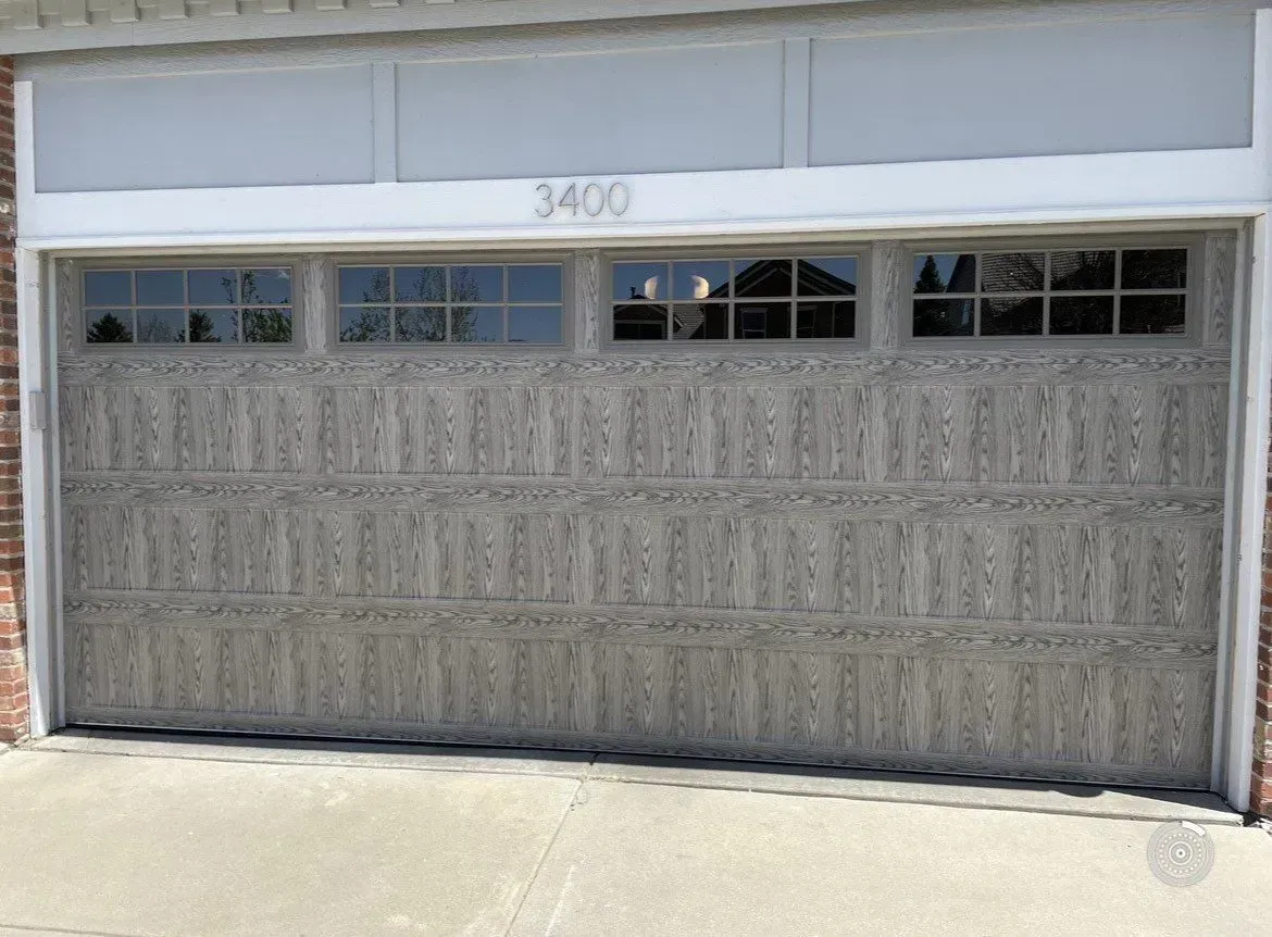 White garage door with small windows above, front of a house with the number 3400.