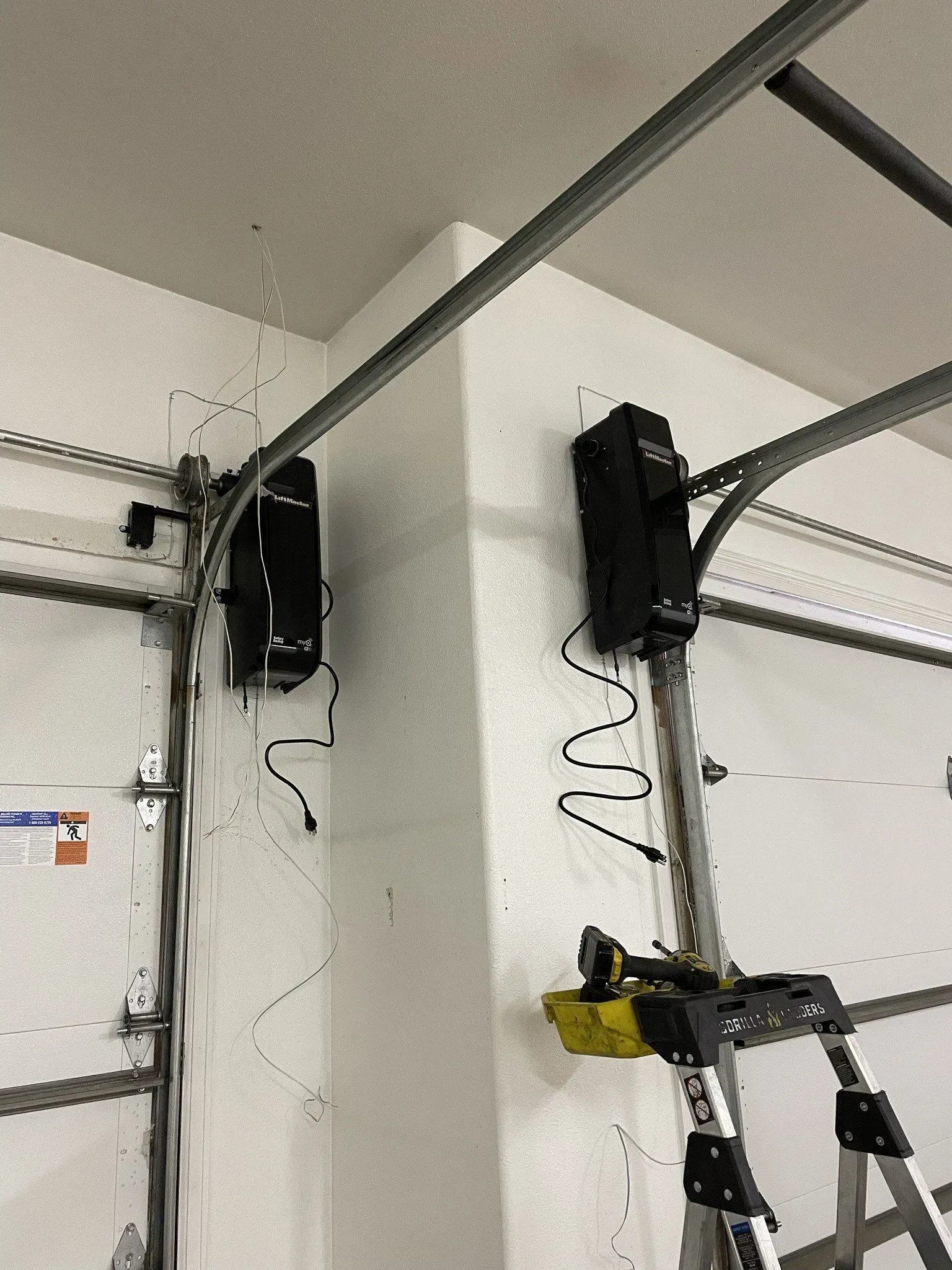 Garage ceiling with a mounted garage door opener and metal track over a ladder.