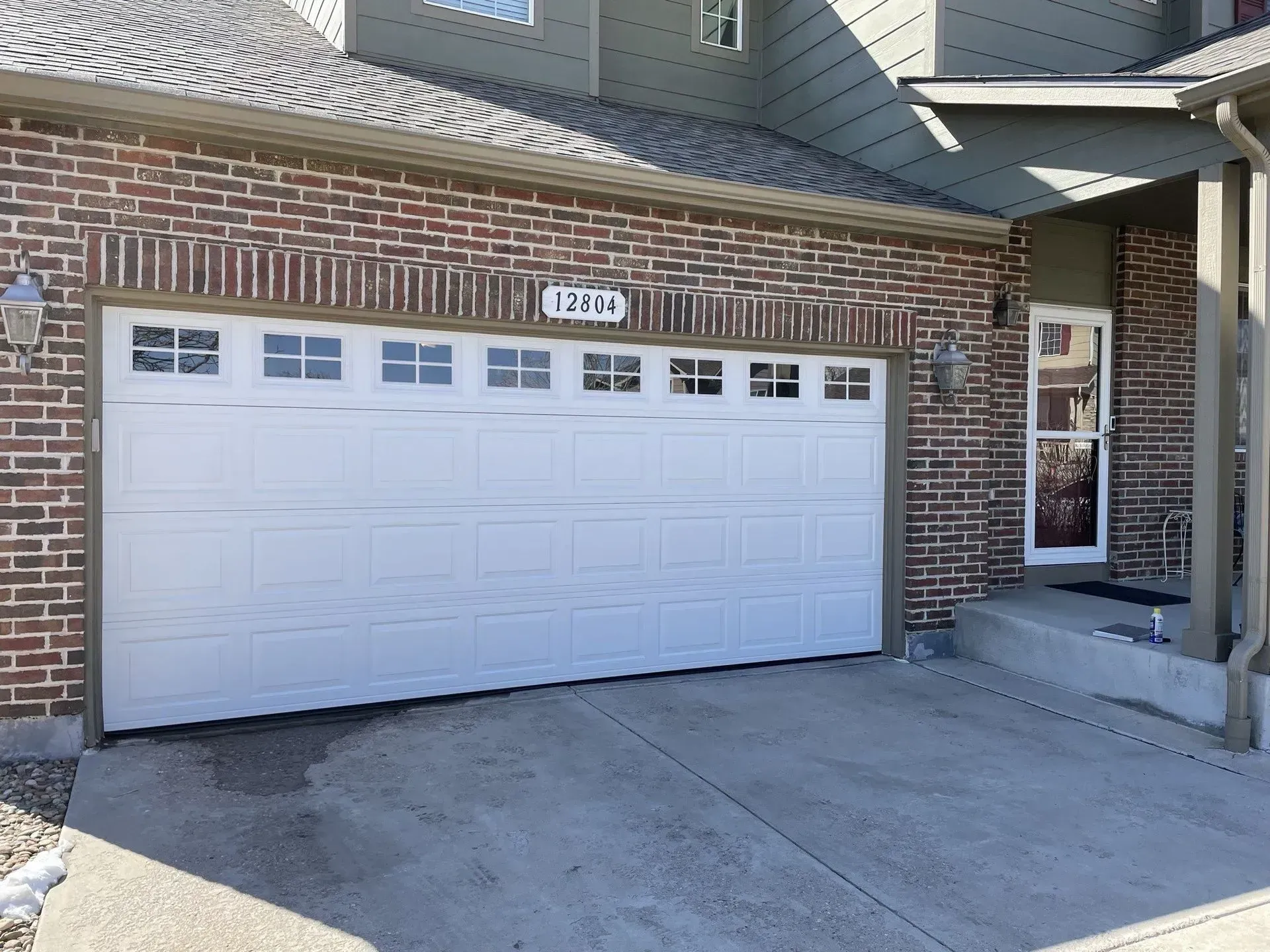 Brick house front with white garage door and concrete driveway