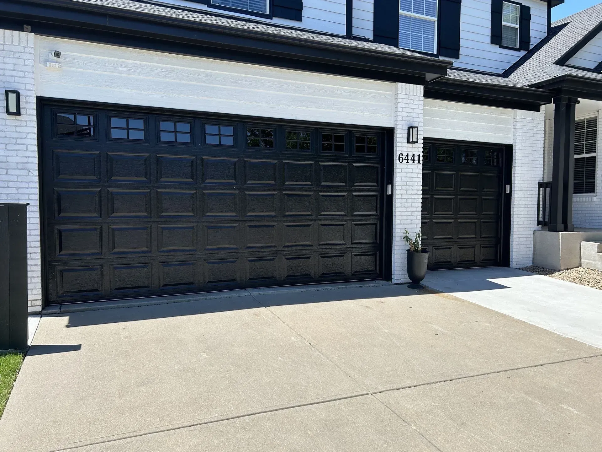 Modern house exterior with black garage doors and a concrete driveway