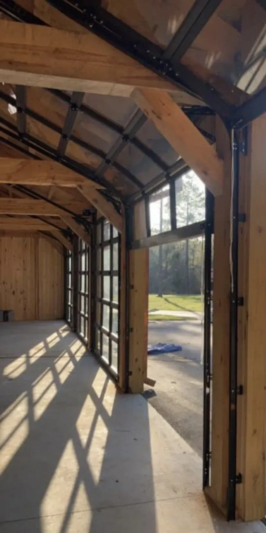 Wooden-framed shed interior with open doorway and sunlight casting long shadows on the floor