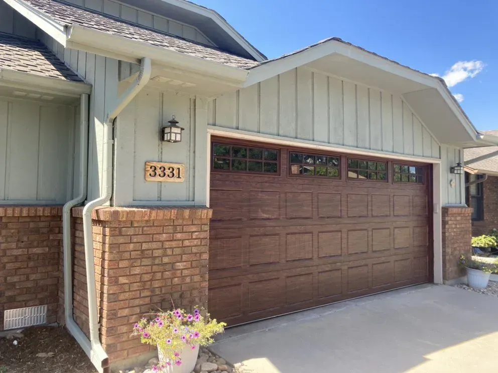 House garage with brown paneled door, brick accents, and house number 3318 above the entry
