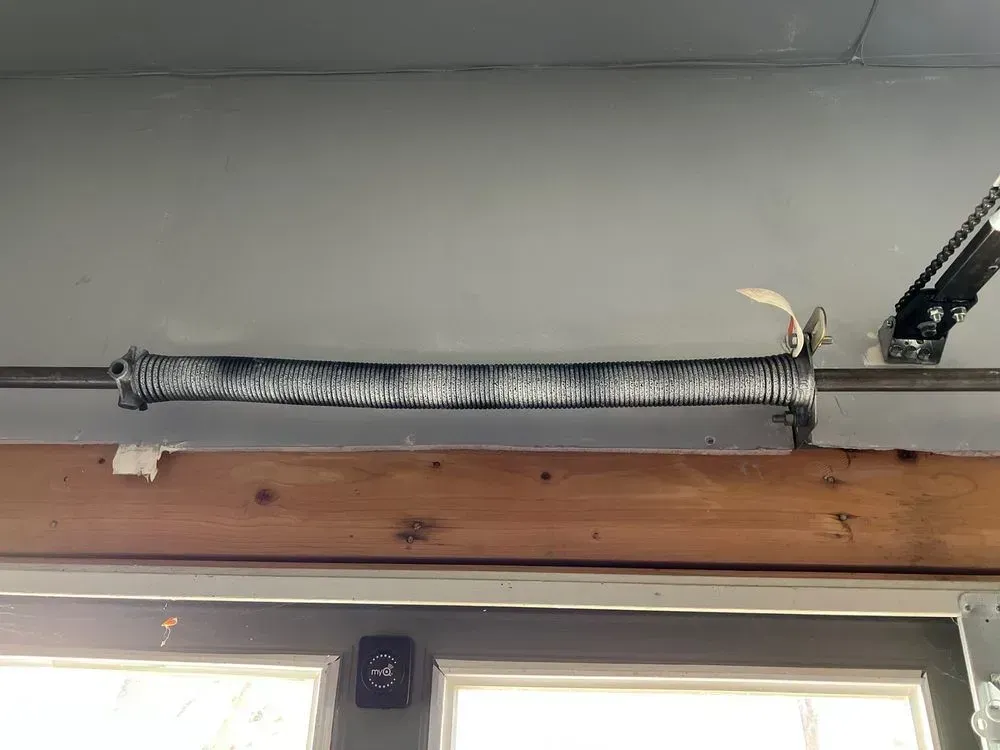 Coiled garage door spring mounted above a wooden door frame