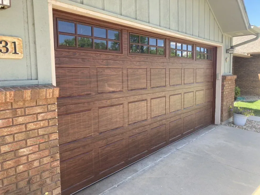 Brown garage door with upper windows on a brick house exterior