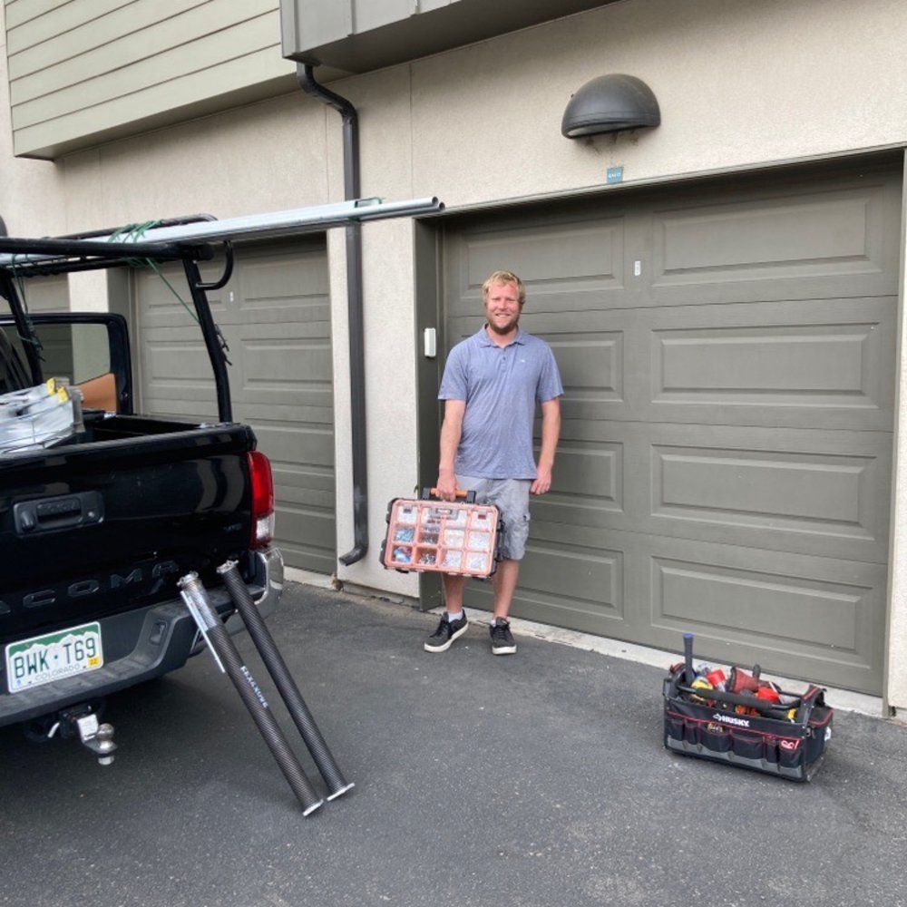 A man is standing in front of a garage door holding a toolbox