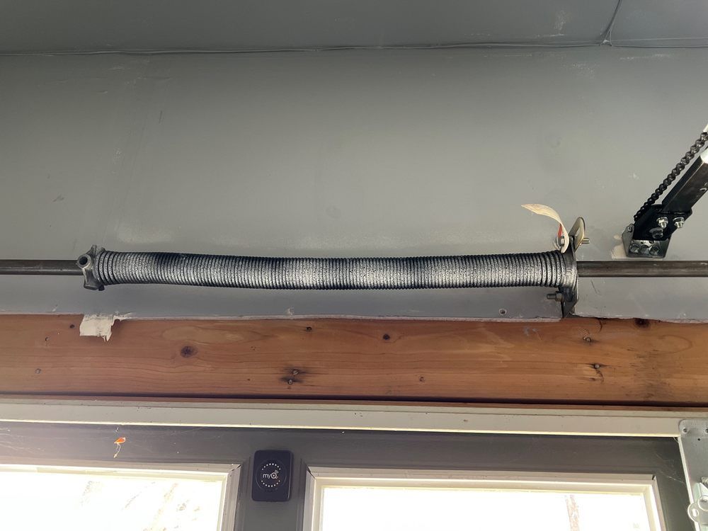 A garage door spring is hanging from the ceiling of a garage.