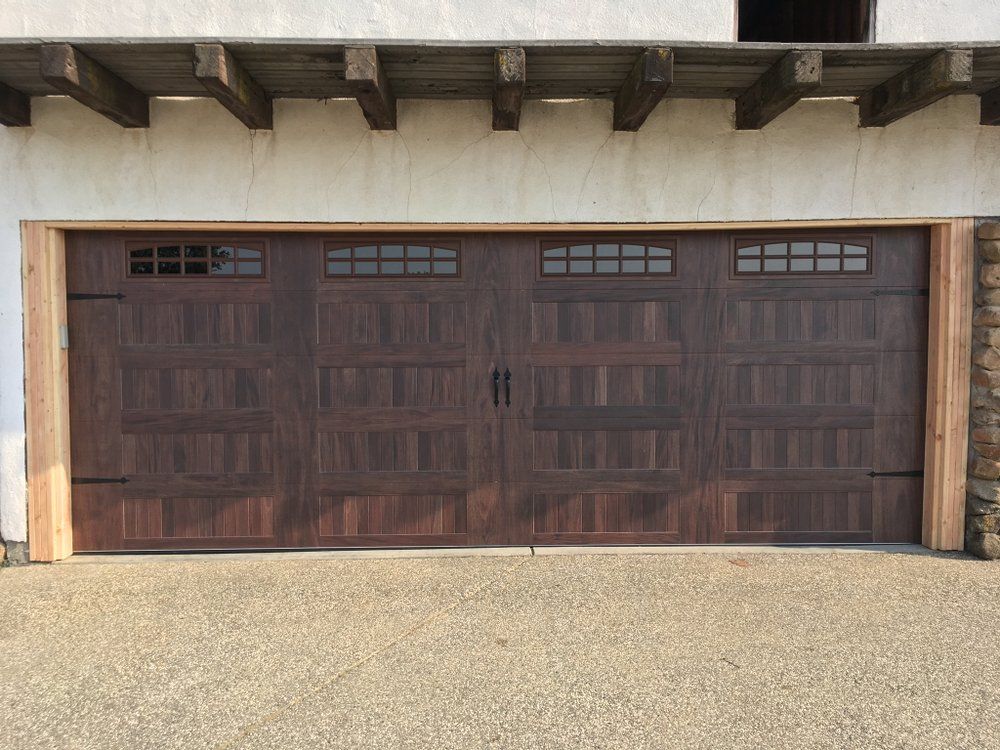 A large wooden garage door is sitting in front of a white building.