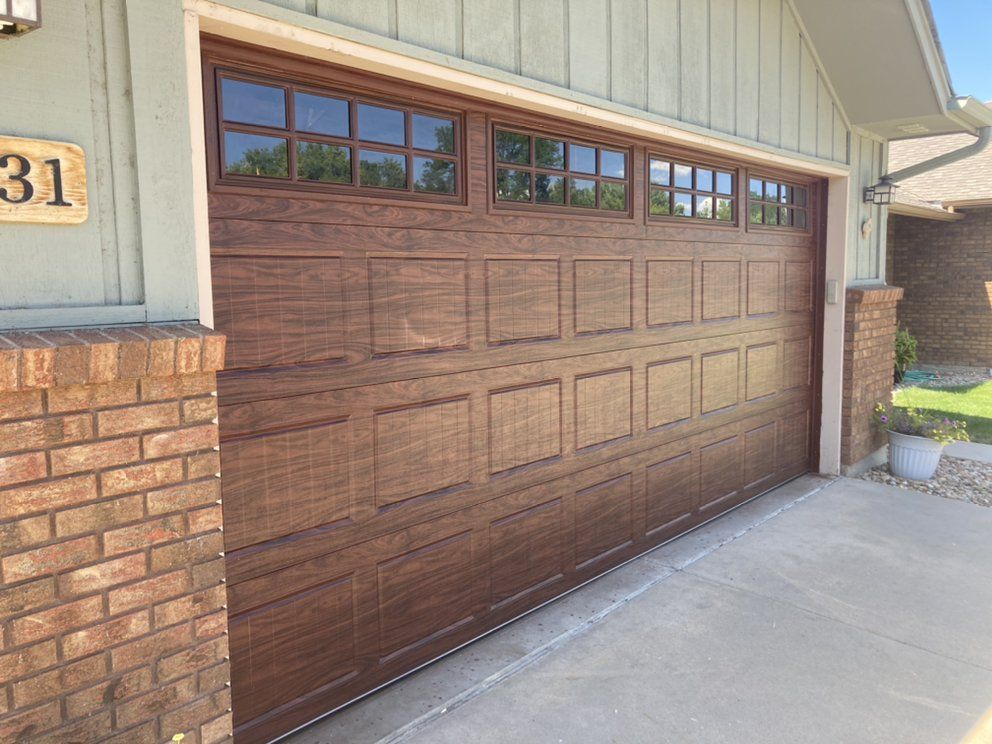A wooden garage door is sitting in front of a brick building.