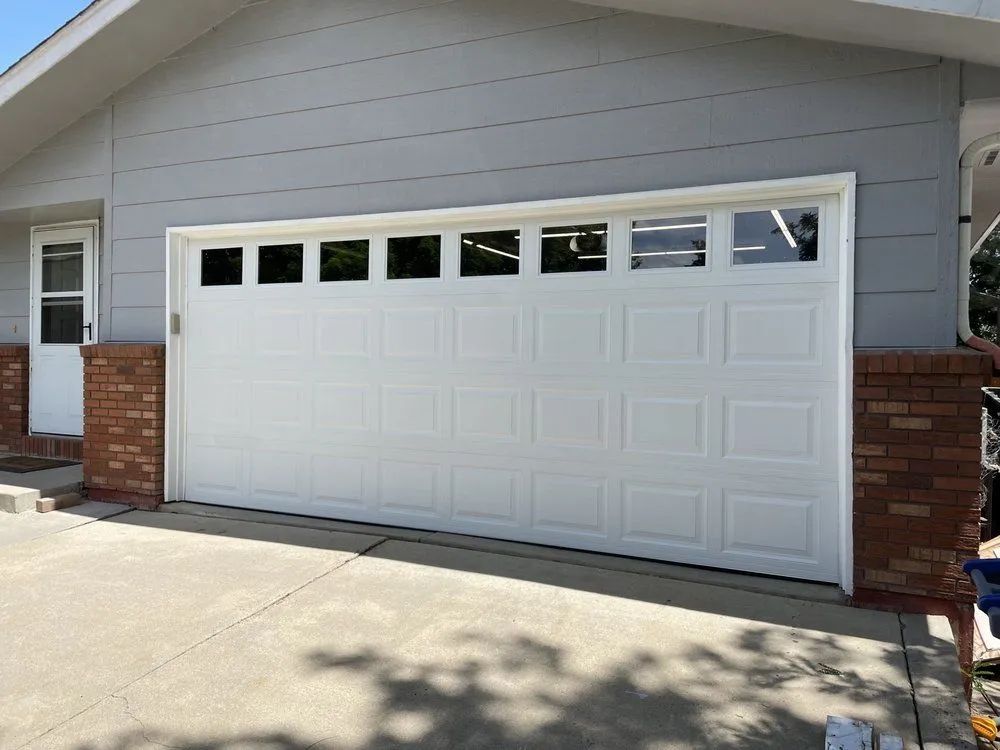 White garage door on a suburban house with brick accents and a concrete driveway