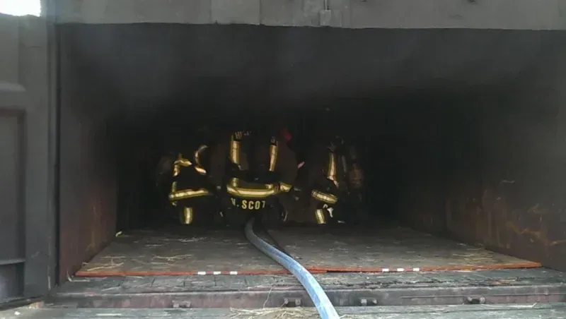 A hose is connected to a stove in a dark room.