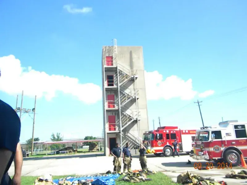 A fire truck is parked in front of a fire training tower.
