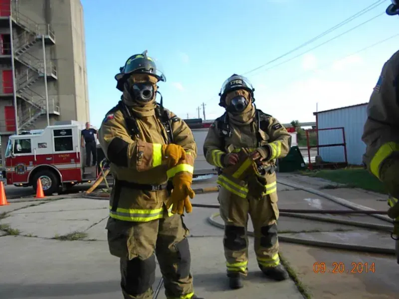 Two firefighters standing in front of a fire truck