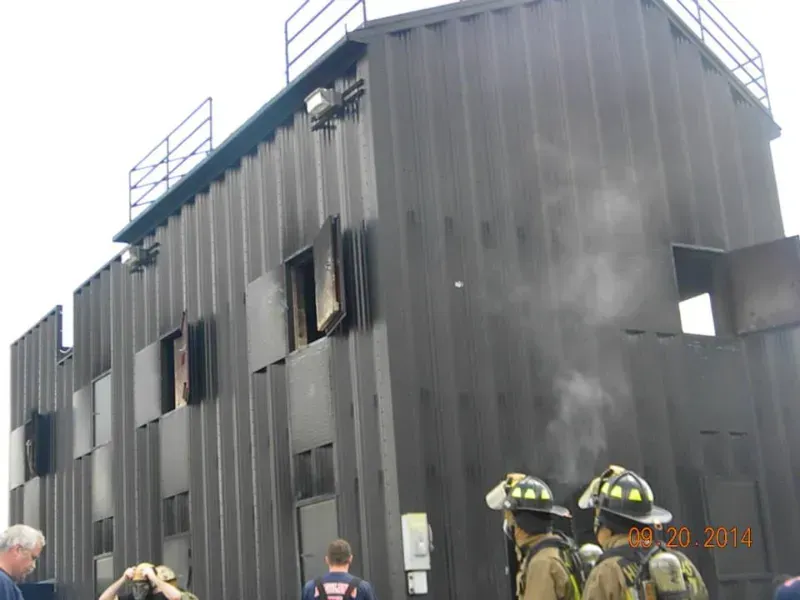 A group of firefighters standing in front of a training building
