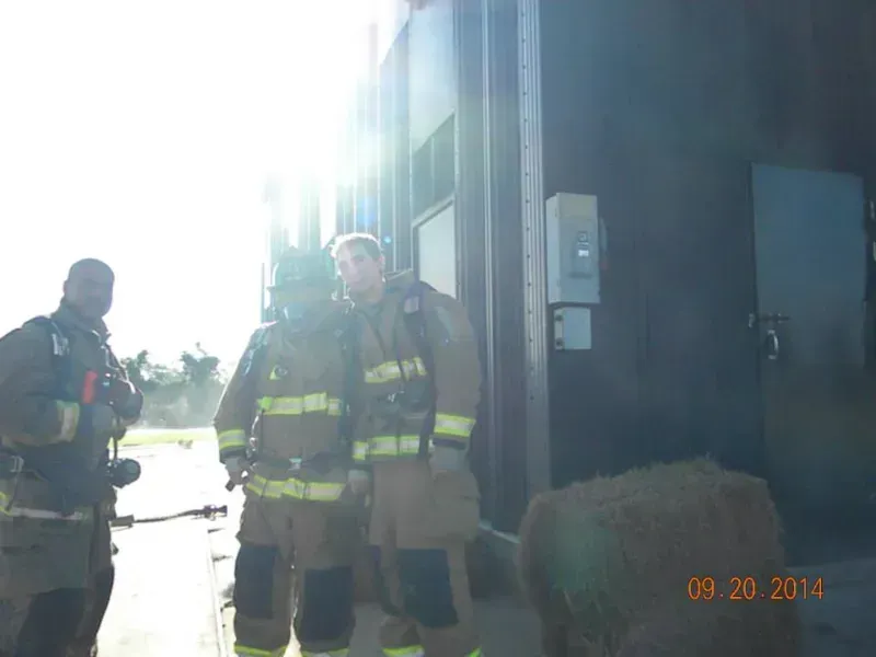 A group of firefighters are standing in front of a training building.