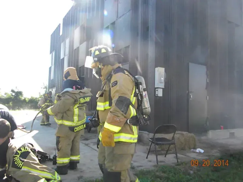 A group of firefighters are standing outside of a training building.