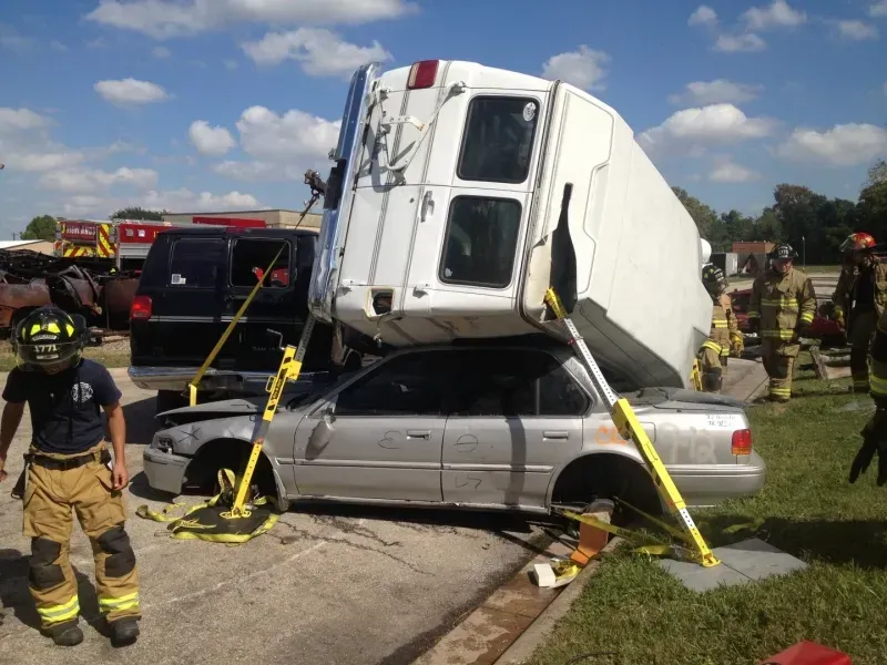 A white van is sitting on top of a silver car