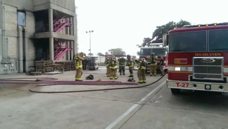 A group of firefighters are standing in front of a fire training building.