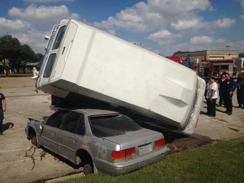 A white van is sitting on top of a silver car