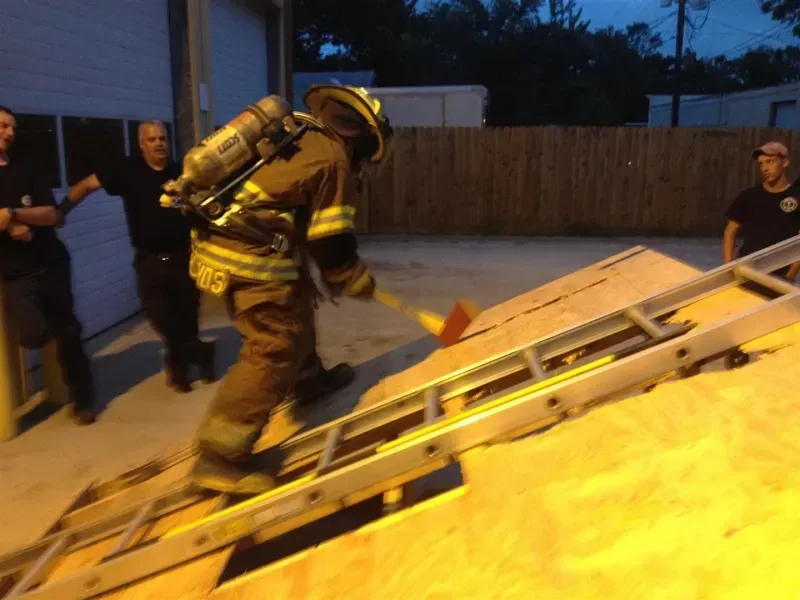 A fireman wearing a helmet is climbing a ladder