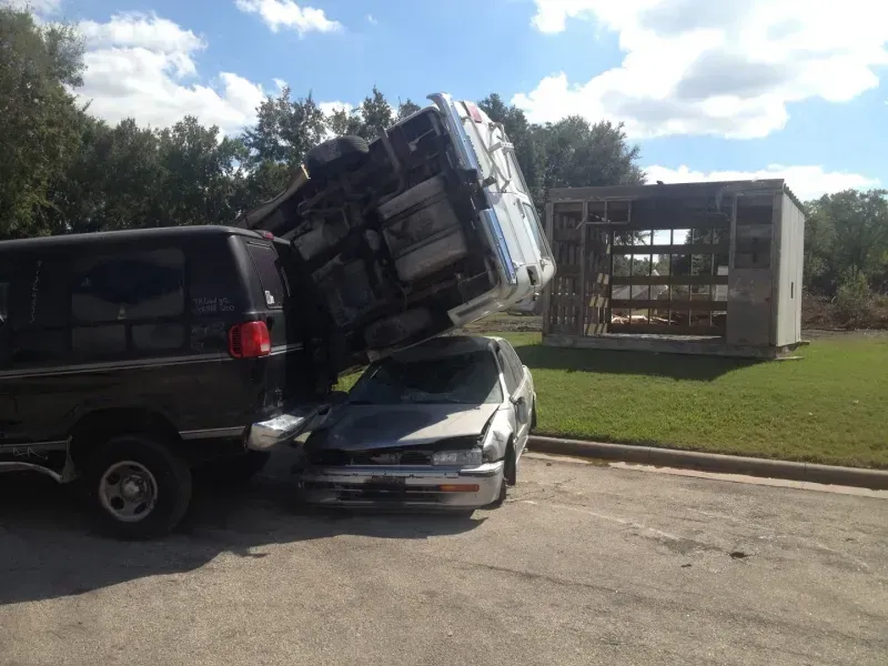 A car is sitting on top of a truck in a parking lot