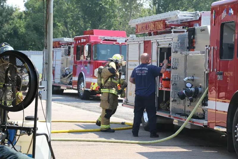 A group of firefighters are standing next to a fire truck.