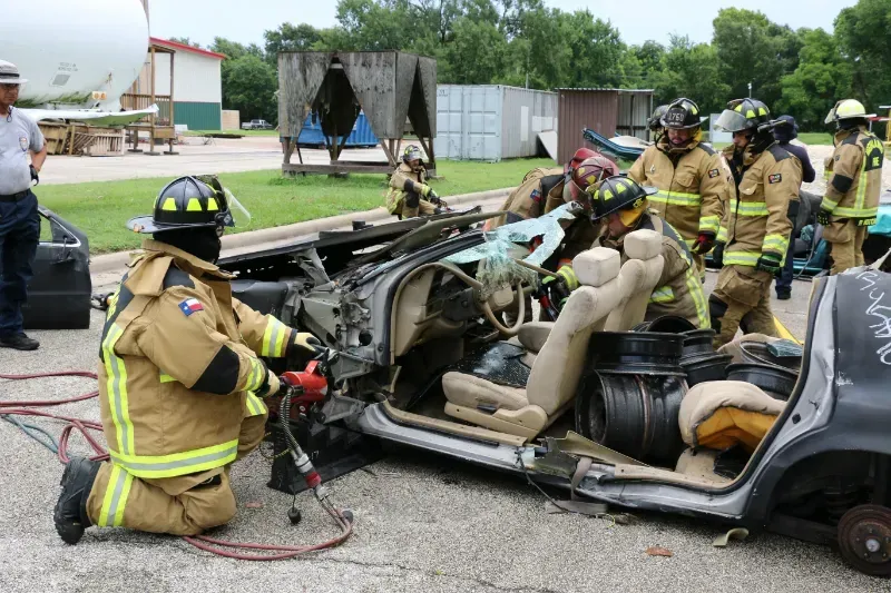 A group of firefighters are working on a wrecked car.