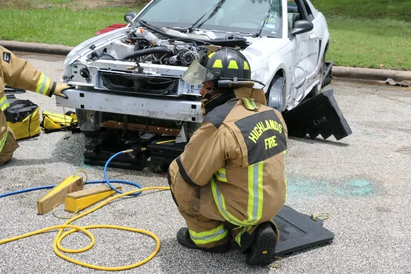 A fireman in a highland fire uniform is working on a car
