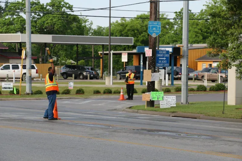 A couple of firefighters standing on the side of the road holding fire boots for MDA fill the boot.
