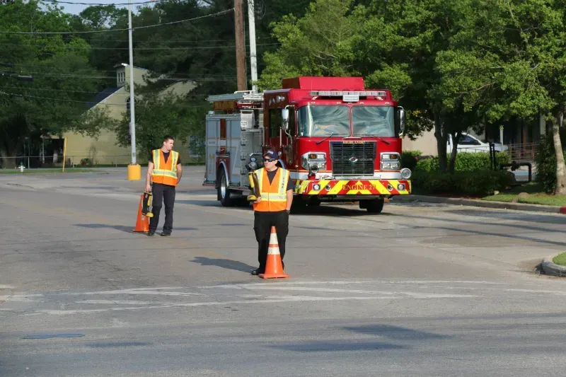 Two men are standing in front of a fire truck holding fire boots for MDA fill the boot.