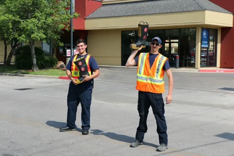 Two men in safety vests are standing in front of a building