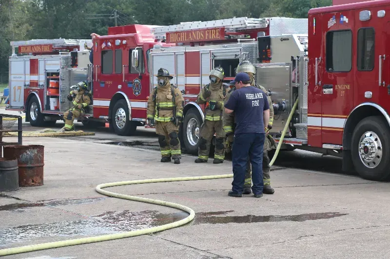 A group of firefighters are standing in front of a row of fire trucks ..