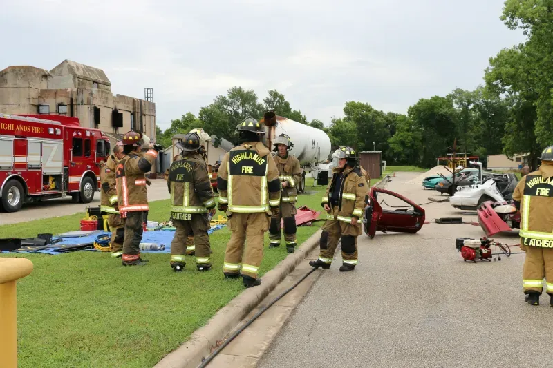 A group of firefighters are standing on the side of the road