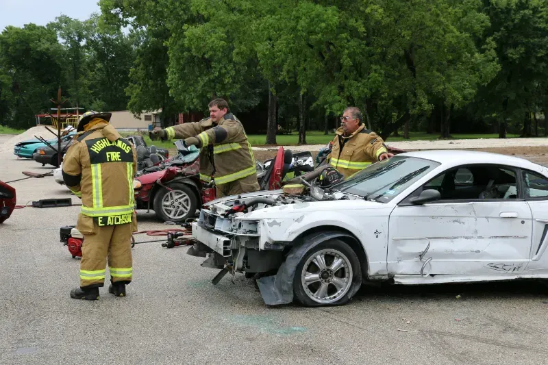 A group of firefighters are working on a wrecked car.