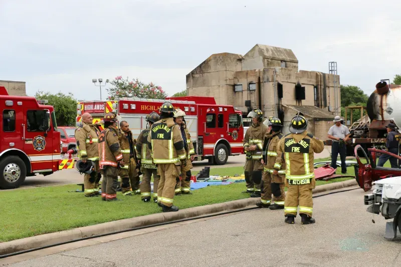 A group of firefighters are standing in front of a fire truck on the side of the road.