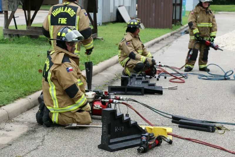 A group of firefighters are kneeling down on the side of the road.