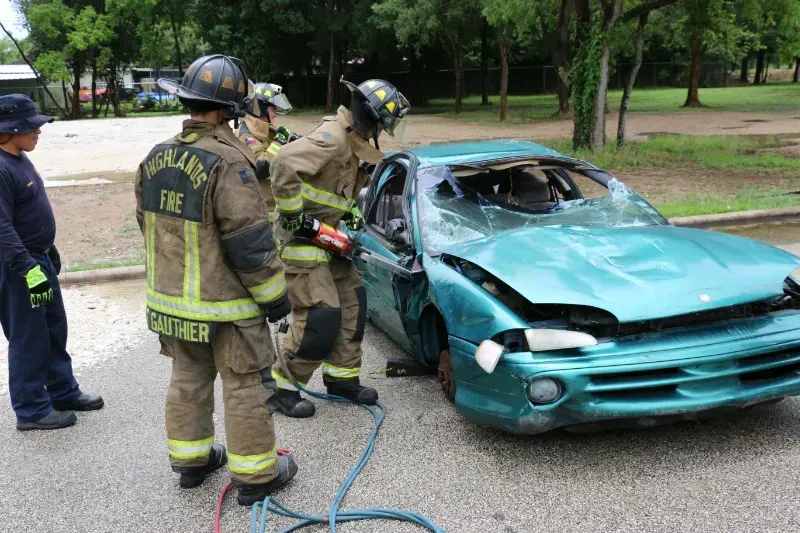 A group of firefighters are working on a wrecked car.