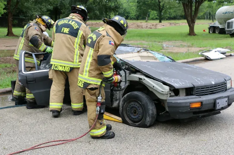 A group of firefighters are working on a damaged car.