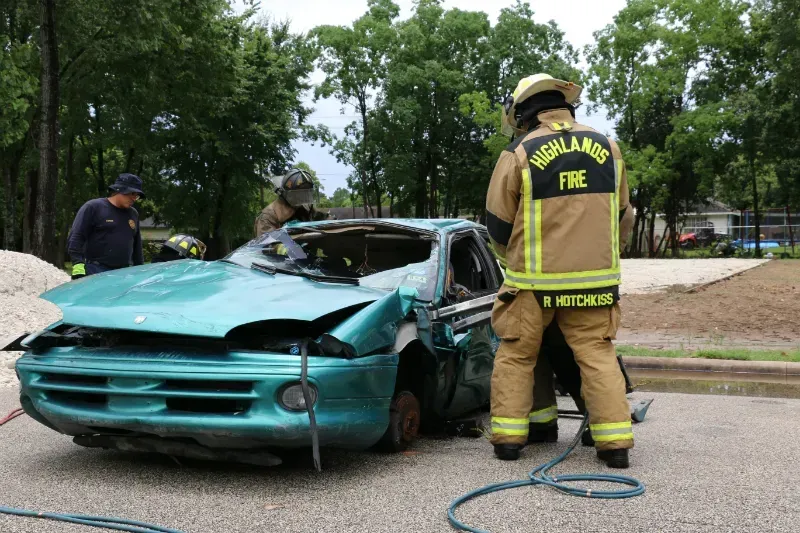 A firefighter is standing next to a wrecked car.