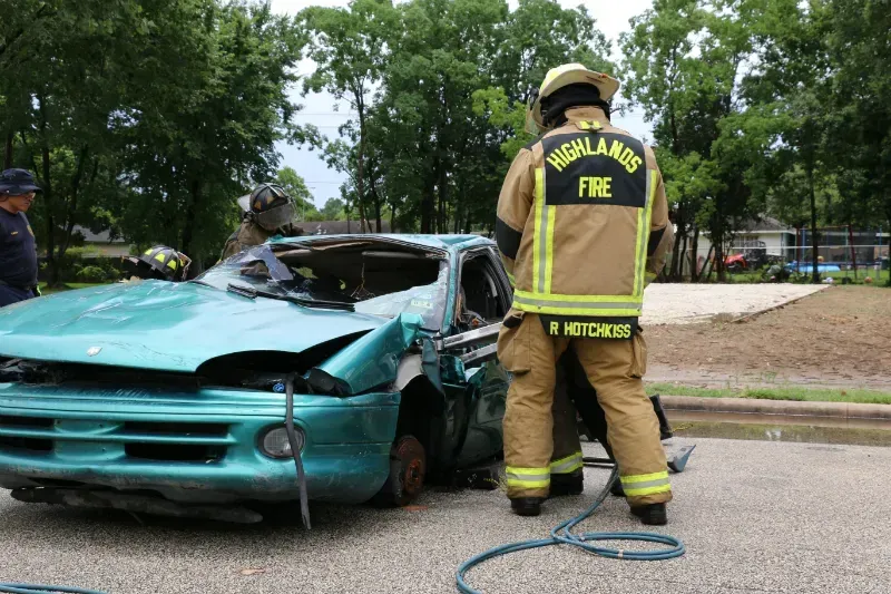 A firefighter is standing next to a wrecked car.