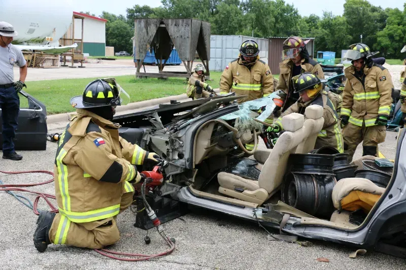 A group of firefighters are working on a wrecked car.