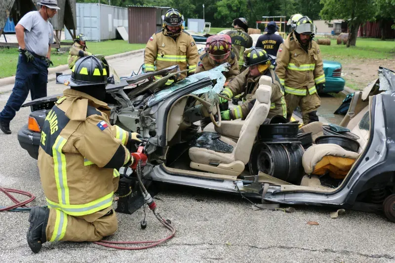 A group of firefighters are working on a wrecked car
