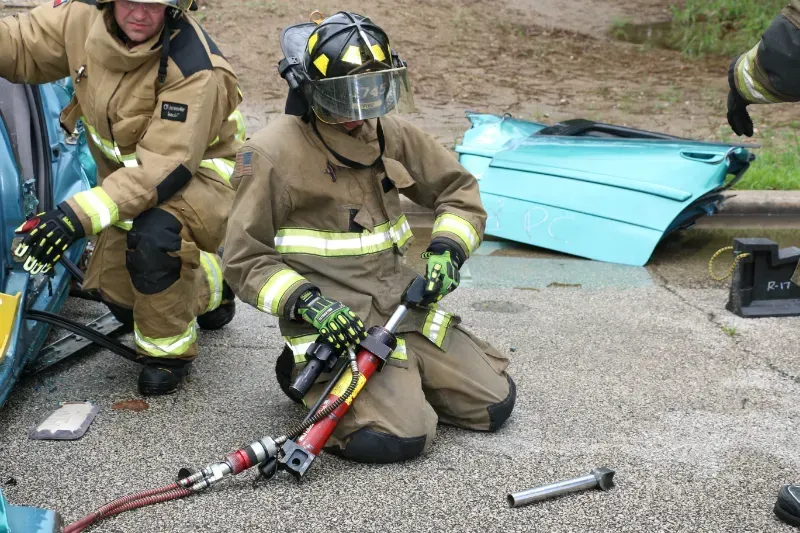 A group of firefighters are working on a car