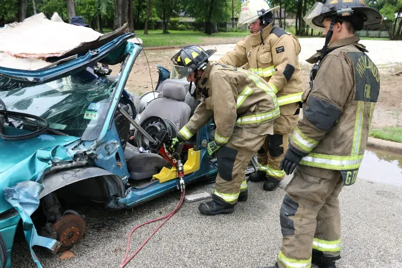A group of firefighters are working on a wrecked car.
