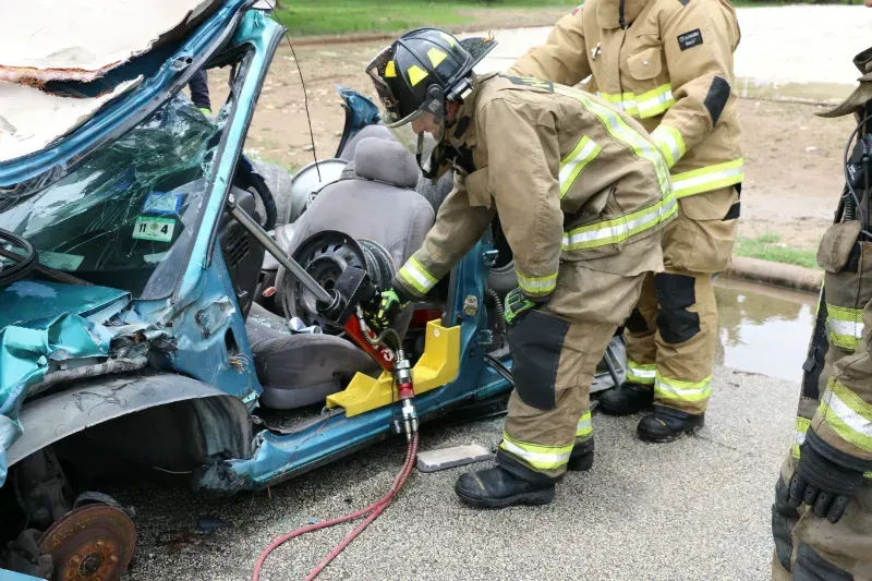 A group of firefighters are working on a wrecked car.