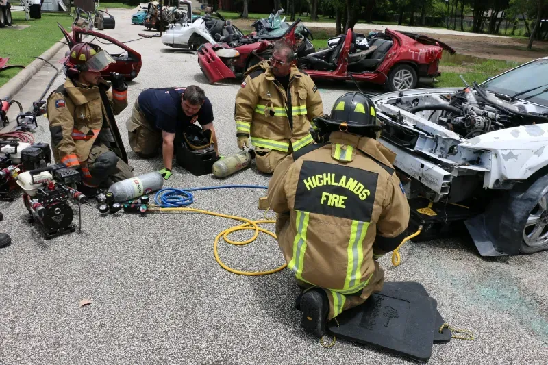 A group of firefighters from the highlands fire department are working on a car