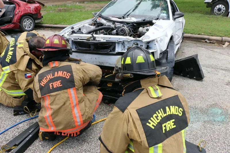 A group of firefighters are working on a wrecked car.