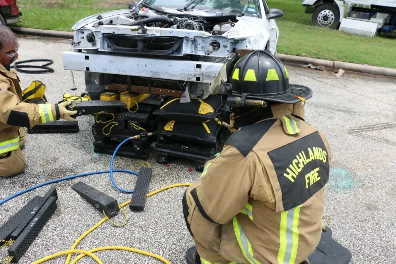 A group of firefighters are working on a staged wrecked car during an extrication exercise.